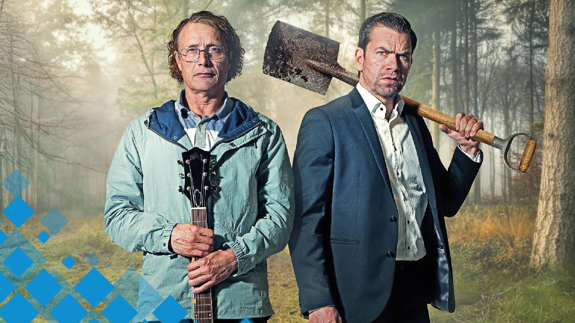 Deux hommes sont dans les bois. Un tient une guitare dans ses mains, l'autre tient une pelle.